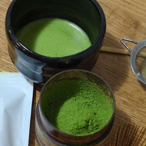 a bowl of usucha and a tea caddy full of green tea powder
